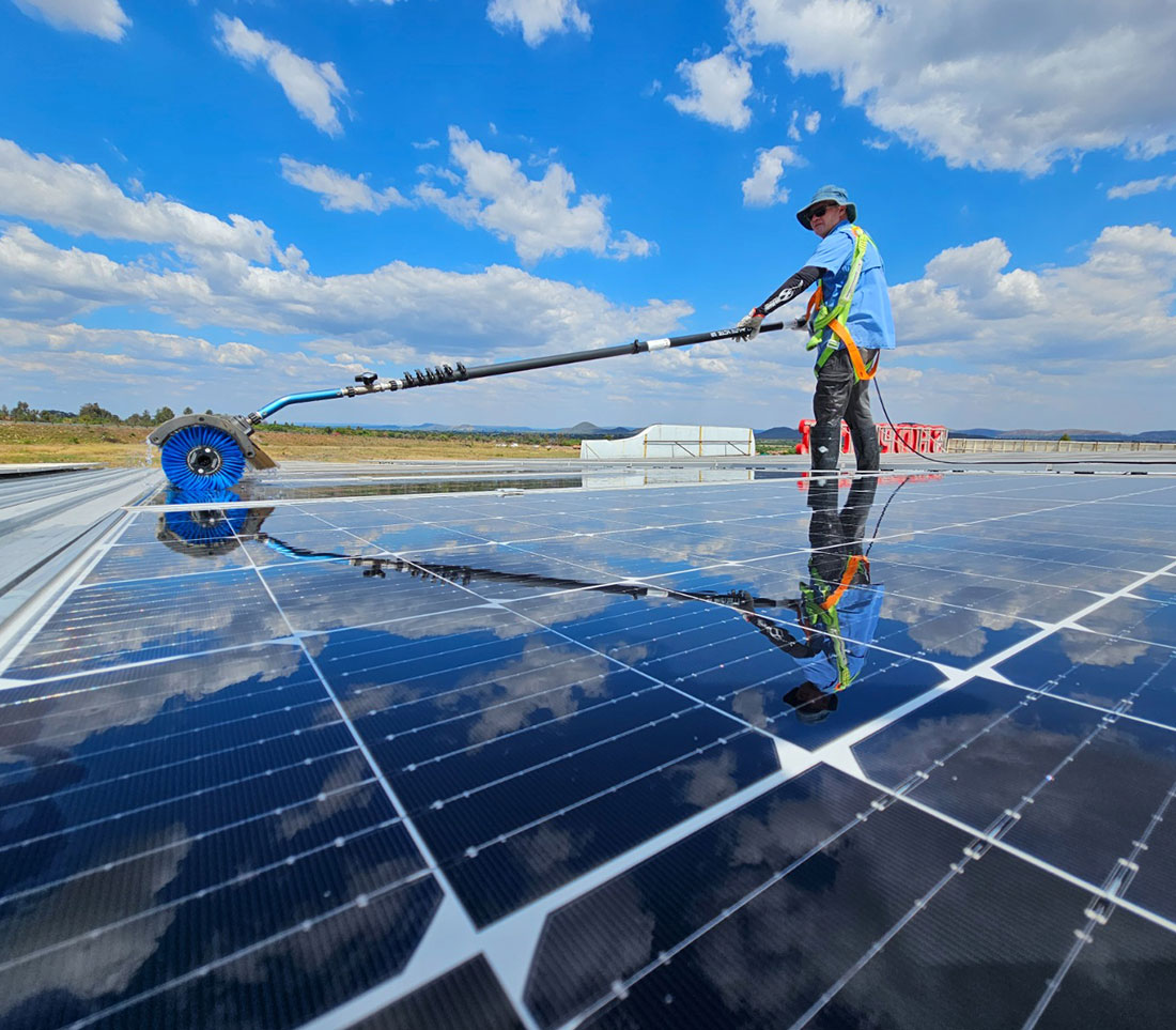 Technician cleaning a solar array with a Cleantecs brush pole